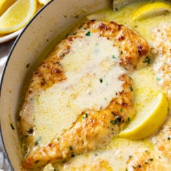 Creamy Lemon Chicken in a skillet with lemon wedges and parsley.