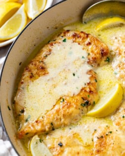 Creamy Lemon Chicken in a skillet with lemon wedges and parsley.