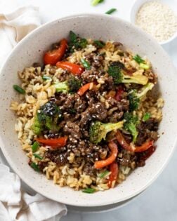 A bowl of ground beef and broccoli over rice with bell peppers.