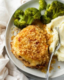 Parmesan Crusted Chicken with broccoli and mashed potatoes on a white plate with a fork.