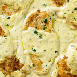 Seared chicken in a skillet with Creamy Herb Sauce.