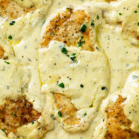 A seared chicken breast in a creamy herb sauce with parsley on top.