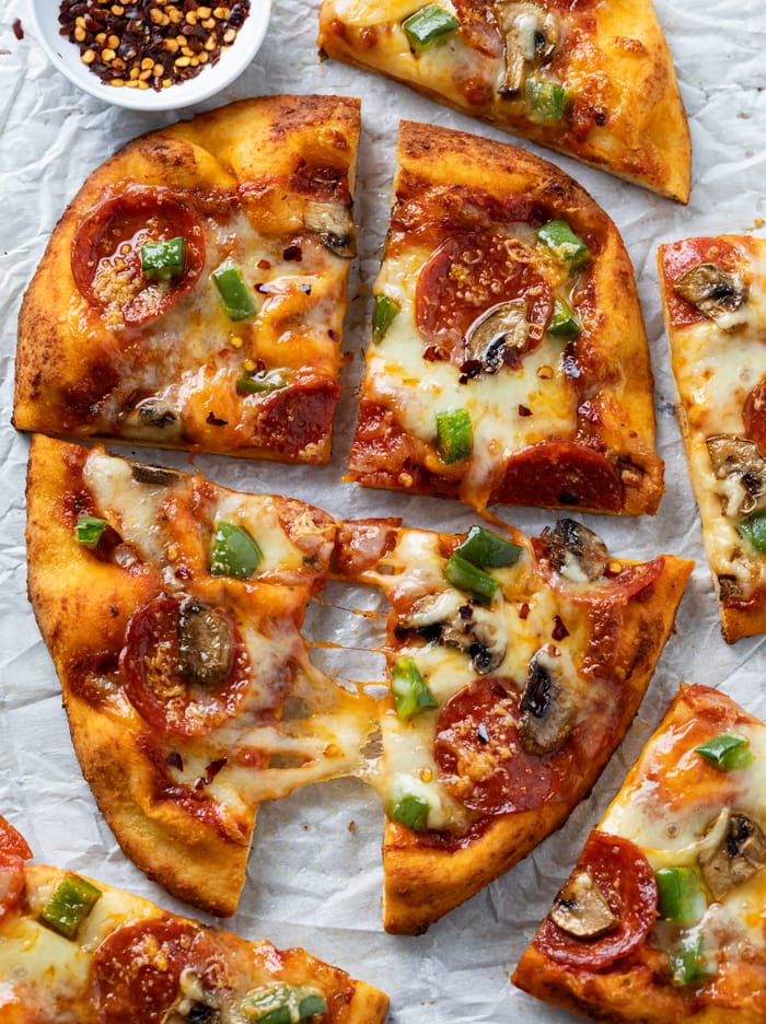 Sliced Naan bread pizza with melted cheese and pepperoni, mushrooms, and peppers.
