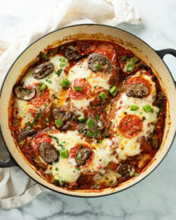 A round skillet filled with Pizza Chicken with mozzarella cheese and pizza toppings.