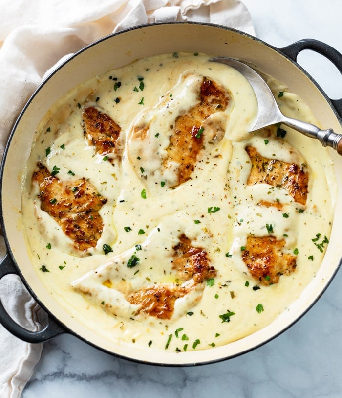A skillet filled with seared chicken in a creamy ranch sauce with parsley on top.