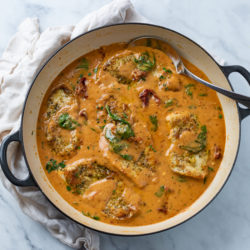 A pot of creamy Tuscan Chicken in sauce with tomatoes and spinach.