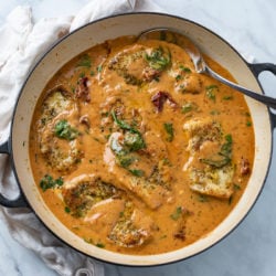 A pot of creamy Tuscan Chicken in sauce with tomatoes and spinach.