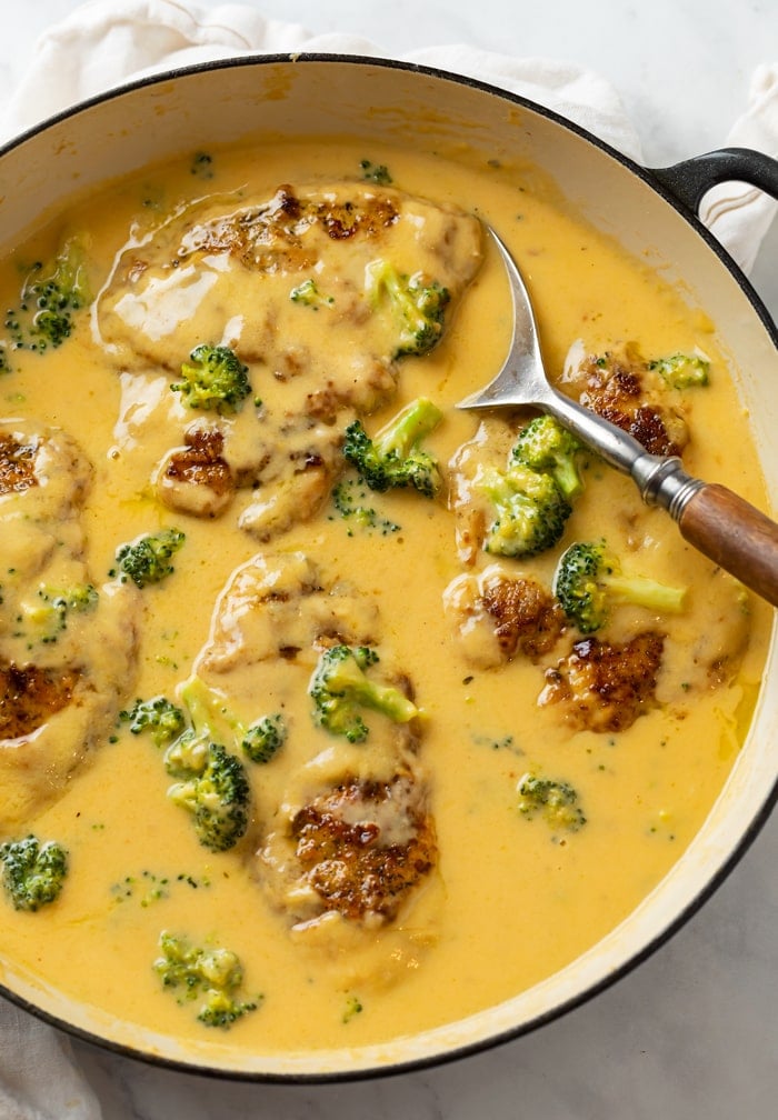 A skillet of Chicken in a creamy cheese sauce with broccoli.