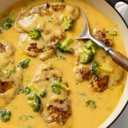 A skillet filled with Cheese Chicken with broccoli and a spoon.