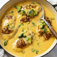 A skillet filled with Cheese Chicken in a creamy cheese sauce with broccoli.