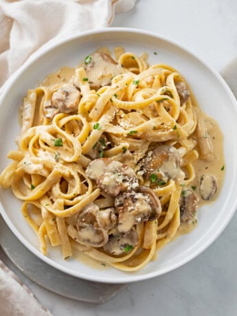 Creamy Mushroom Pasta on a white plate with Parmesan cheese and parsley on top.