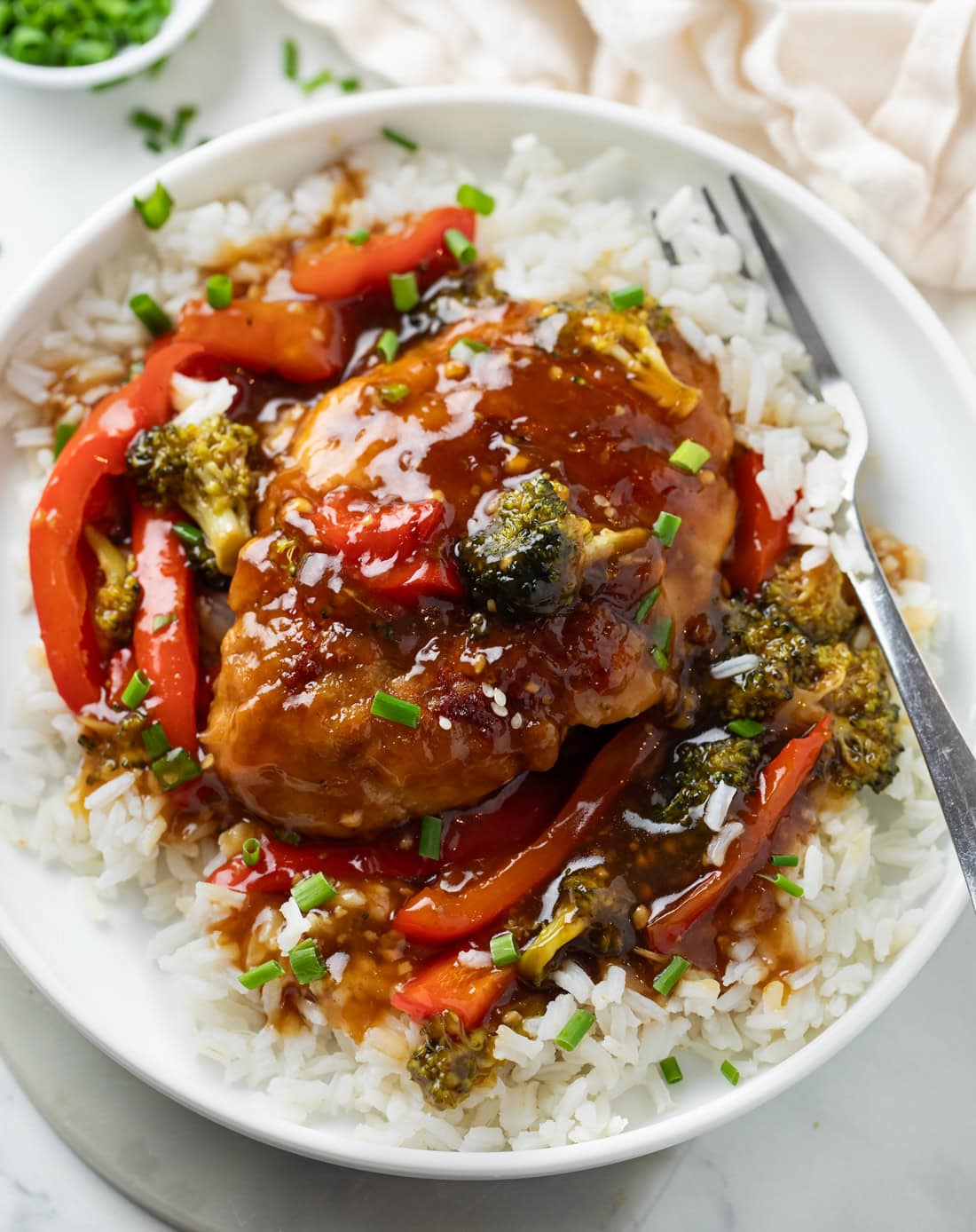Honey Garlic Chicken on a bed of white rice with glaze and vegetables.
