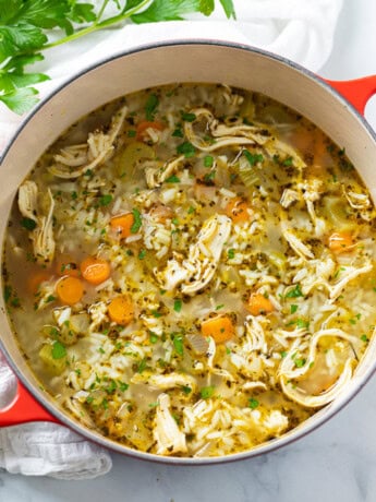 A dutch oven filled with Chicken and Rice Soup with parsley on the side.