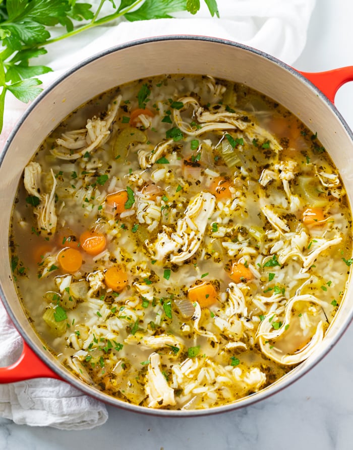 A dutch oven filled with Chicken and Rice Soup with parsley on the side.