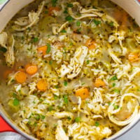 Chicken and rice soup in a soup pot with broth, vegetables, shredded chicken, and rice.
