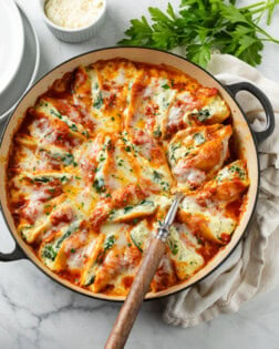 A skillet filled with cheesy Stuffed Shells with mozzarella cheese and parsley on top.