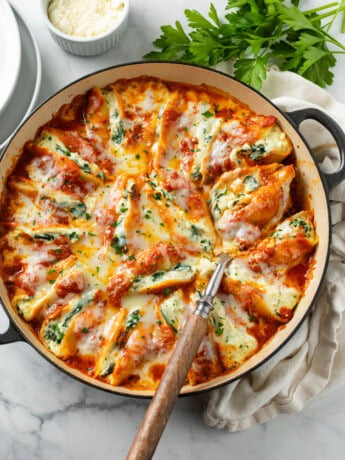 A skillet filled with cheesy Stuffed Shells with mozzarella cheese and parsley on top.