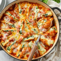 A round baking dish filled with Cheesy Stuffed Shells with sauce and mozzarella cheese.