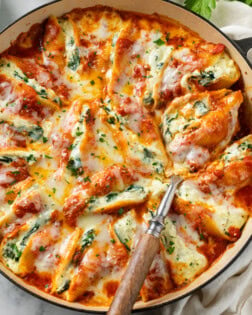 A round baking dish filled with Cheesy Stuffed Shells with sauce and mozzarella cheese.