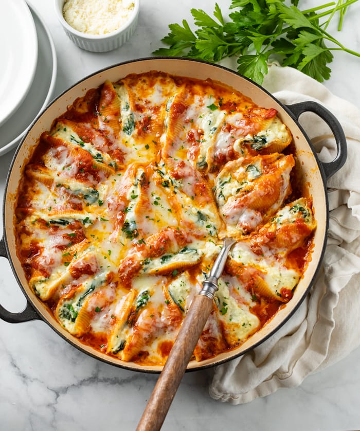 A skillet filled with cheesy Stuffed Shells with mozzarella cheese and parsley on top.