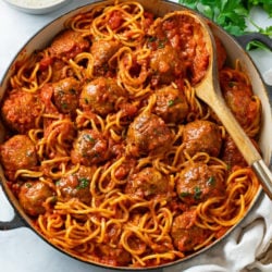 A large pot of Spaghetti and Meatballs with a spoon in it.