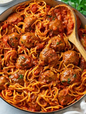 A large pot of Spaghetti and Meatballs with a spoon in it.