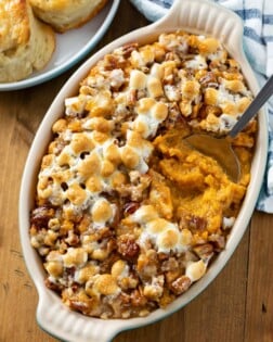 A casserole dish with sweet potato casserole in to with marshmallows on top.