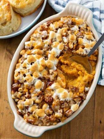 A casserole dish with sweet potato casserole in to with marshmallows on top.