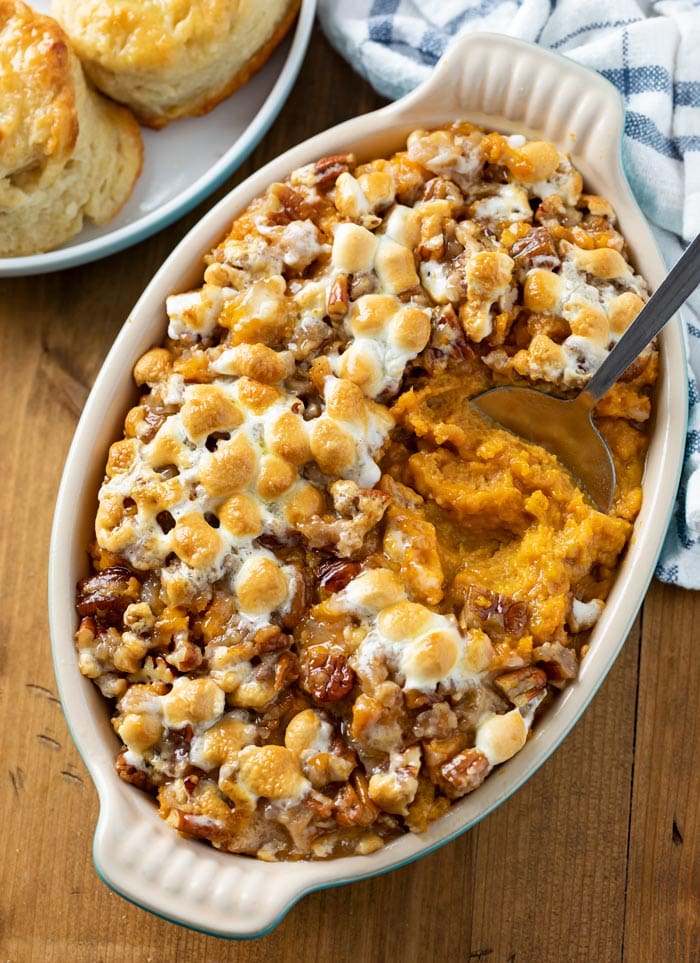 A casserole dish with sweet potato casserole in to with marshmallows on top.