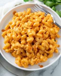 A white plate with Buffalo Chicken Mac and Cheese and a fork on the side.