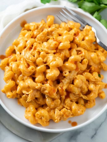 A white plate with Buffalo Chicken Mac and Cheese and a fork on the side.