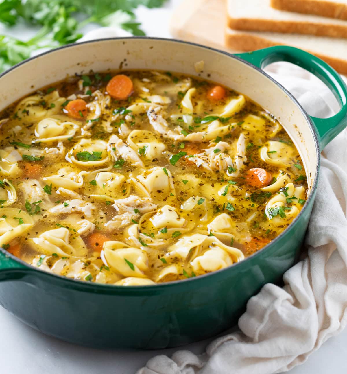 Chicken Tortellini Soup in a green soup pot with vegetables and broth.