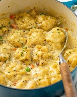 A blue Dutch oven filled with Chicken and Dumplings with chicken and vegetables.