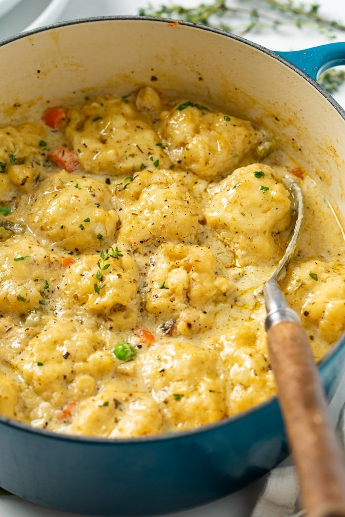 A blue Dutch oven filled with Chicken and Dumplings with chicken and vegetables.