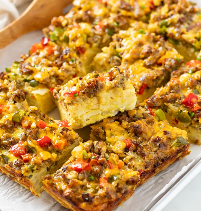 Slices of Hashbrown Breakfast Casserole topped sausage, cheese, and peppers.