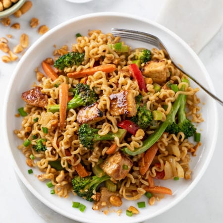Ramen Noodle Stir Fry with Chicken and vegetables in sauce with a fork on the side.