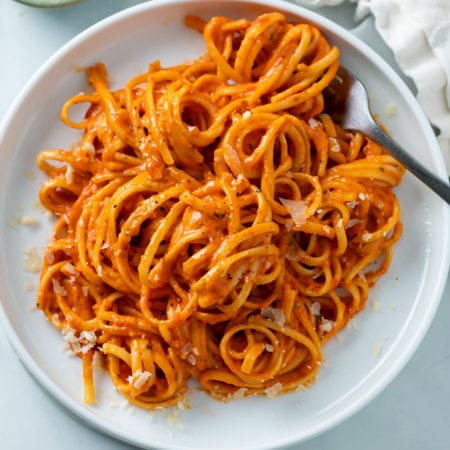 A white plate with Roasted Red Pepper Pasta on top with a fork.