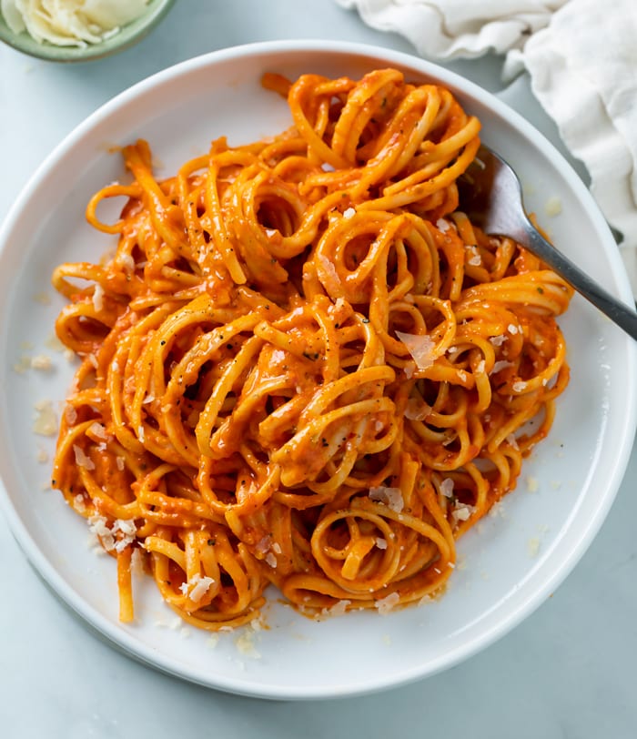 A white plate with Roasted Red Pepper Pasta on top with a fork.