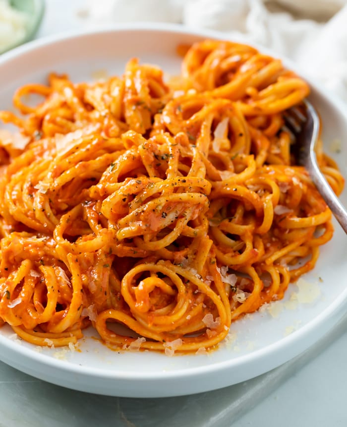 Roasted Red Pepper Pasta on a white plate with a fork in the background.