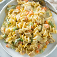 A white plate with Creamy Chicken and Noodles with mixed vegetables.