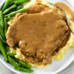 Crock Pot Pork Chops and Gravy on top of Mashed Potatoes with Green Beans.