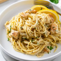 Lemon Chicken Pasta on a white plate with lemon wedges.