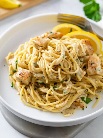 Lemon Chicken Pasta on a white plate with lemon wedges.