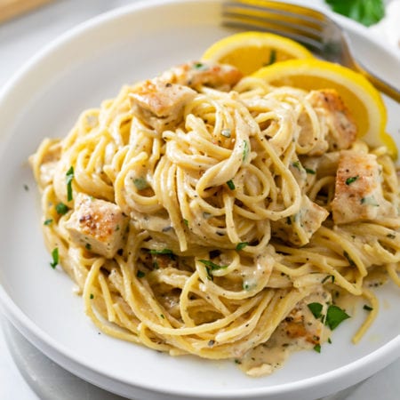 Lemon Chicken Pasta on a white plate with lemon wedges.