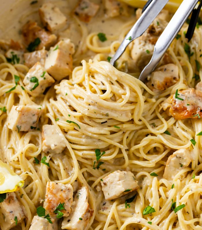 Creamy Lemon Chicken Pasta in a skillet with kitchen tongs.