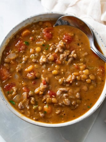 A bowl of Lentil Sausage Soup with a spoon on the side.