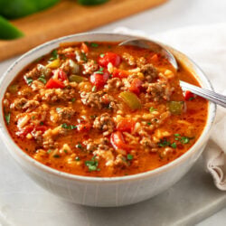 A white bowl filled with Stuffed Pepper Soup with a spoon on the side.