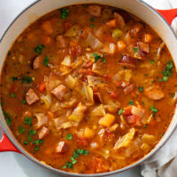 Cabbage Soup with kielbasa, cabbage, and vegetables in a red soup pot.