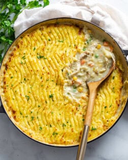 A round dish filled with Chicken Shepherd's Pie with a spoon in it.