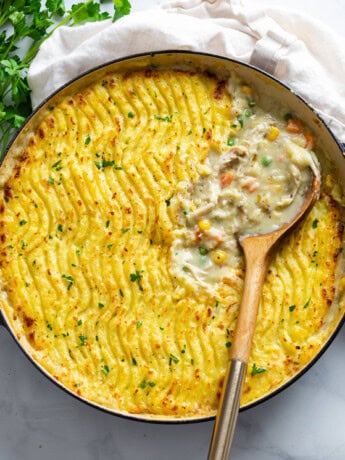 A round dish filled with Chicken Shepherd's Pie with a spoon in it.